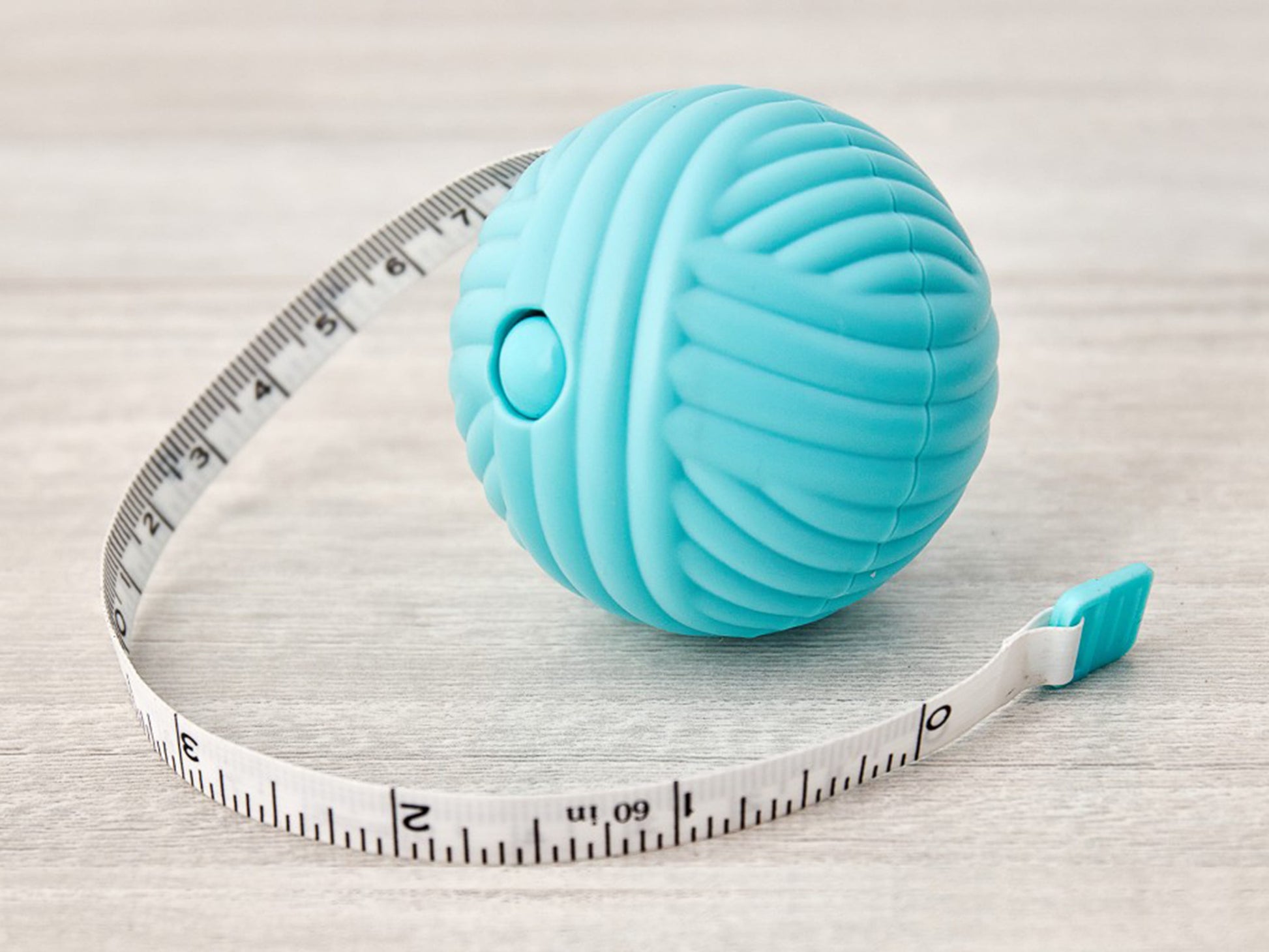 Blue balls that looks like a yarn ball with a tap measure inside. cm and inch